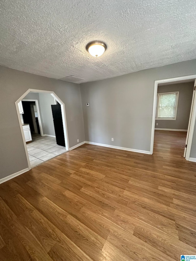 unfurnished room with a textured ceiling and light hardwood / wood-style flooring