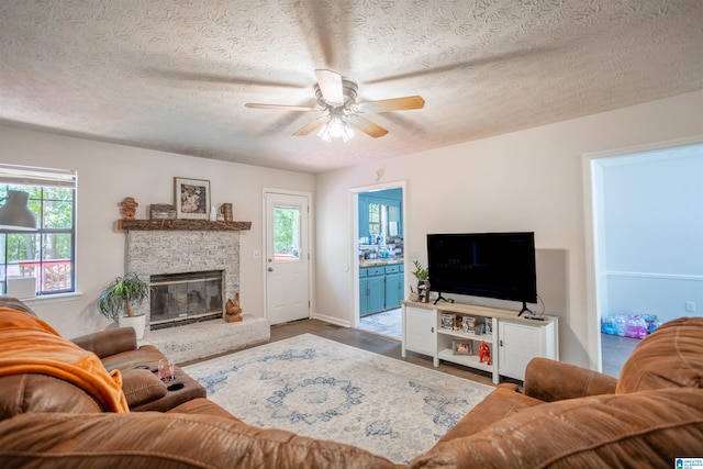 living room with hardwood / wood-style floors, ceiling fan, a fireplace, and a textured ceiling