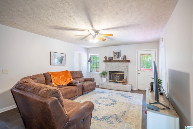 living room with a textured ceiling, ceiling fan, dark hardwood / wood-style floors, and a fireplace