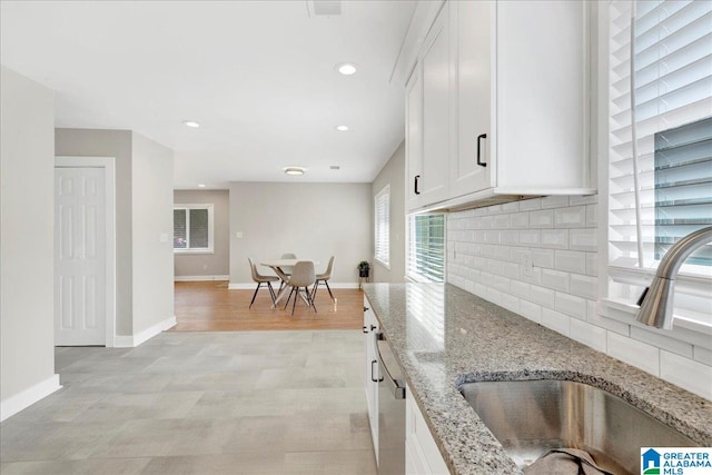 kitchen featuring light stone counters, sink, white cabinetry, and tasteful backsplash