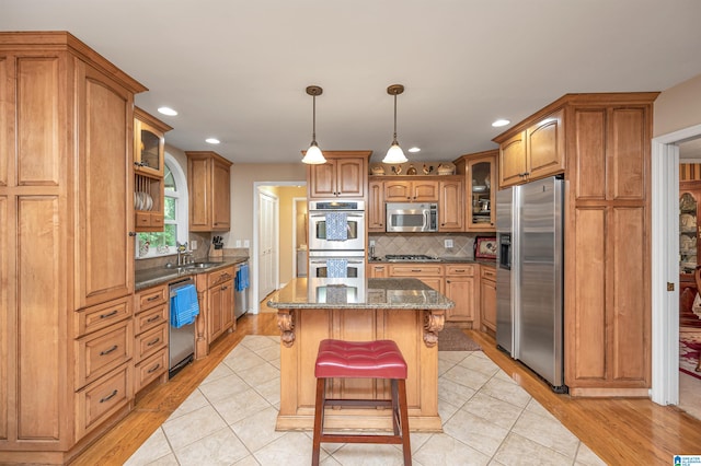 kitchen featuring a kitchen island, backsplash, light hardwood / wood-style floors, stainless steel appliances, and sink