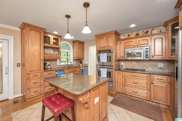 kitchen featuring a breakfast bar area, tasteful backsplash, a center island, stainless steel appliances, and ornamental molding