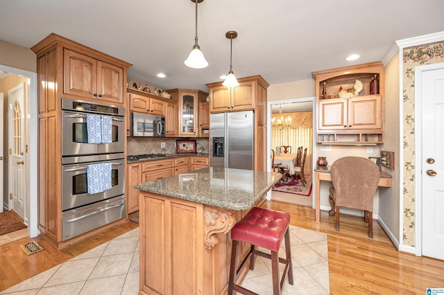 kitchen with a center island, dark stone countertops, appliances with stainless steel finishes, and light wood-type flooring