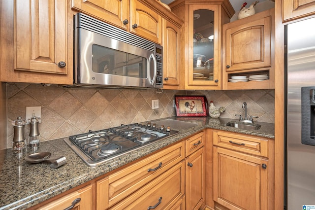 kitchen featuring dark stone countertops, backsplash, stainless steel appliances, and sink