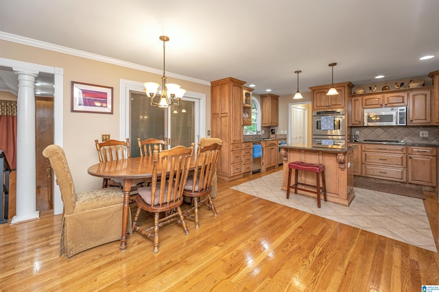 dining room with light hardwood / wood-style flooring, an inviting chandelier, crown molding, and ornate columns