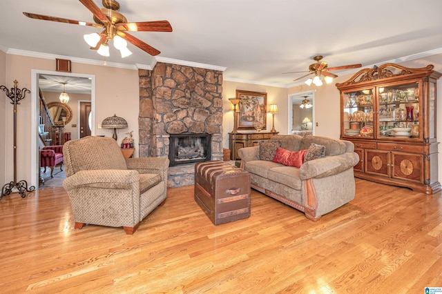 living room with ceiling fan, a fireplace, light hardwood / wood-style floors, and ornamental molding