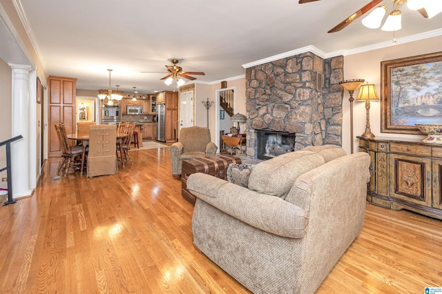 living room with light wood-type flooring, ceiling fan, a fireplace, and ornamental molding