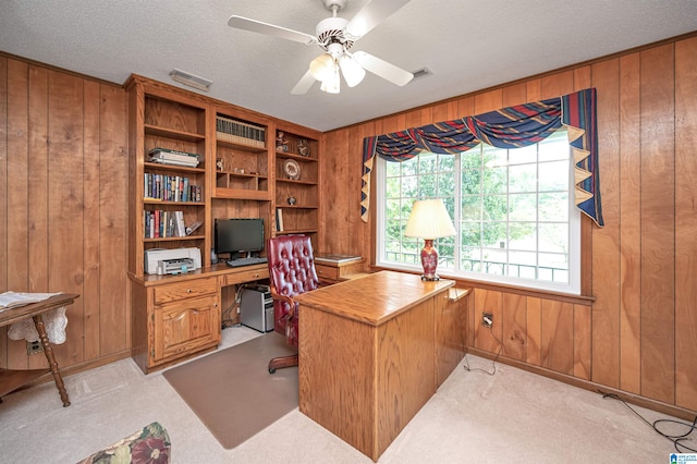 carpeted office featuring a textured ceiling, ceiling fan, and wooden walls