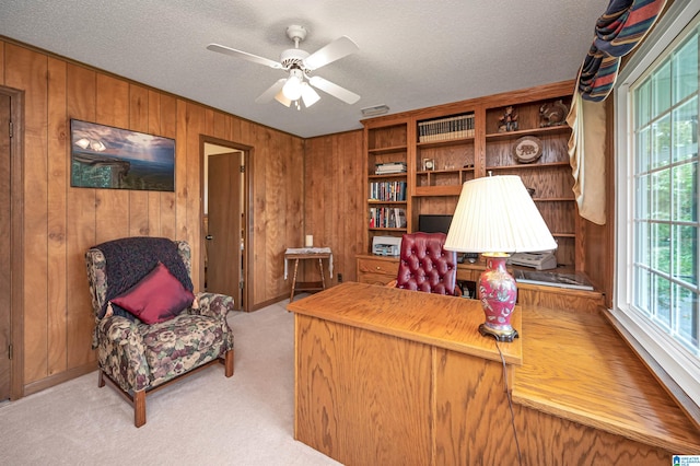 office space featuring ceiling fan, light colored carpet, wooden walls, and a textured ceiling