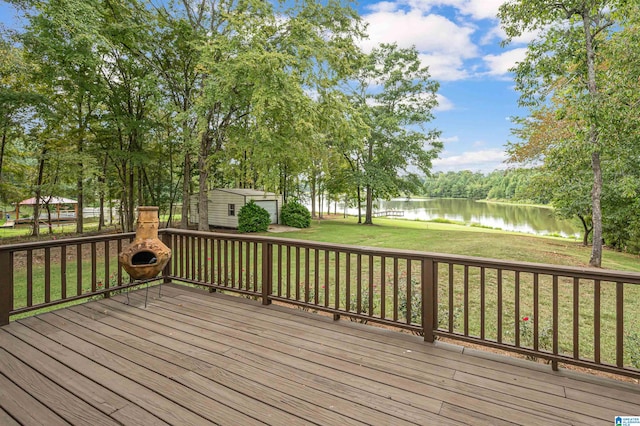 wooden deck with a storage shed, a water view, and a yard