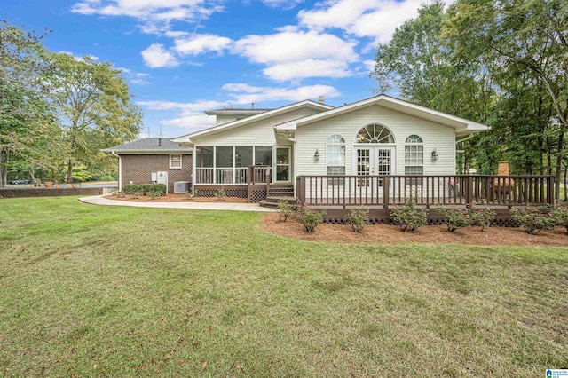 view of front of house featuring a wooden deck, a sunroom, and a front lawn