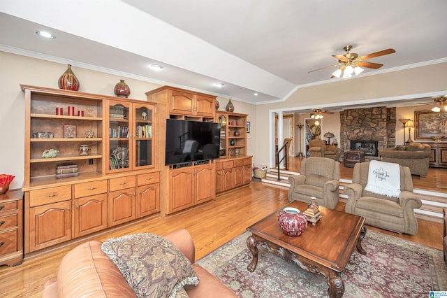 living room with light hardwood / wood-style floors, crown molding, ceiling fan, and a fireplace