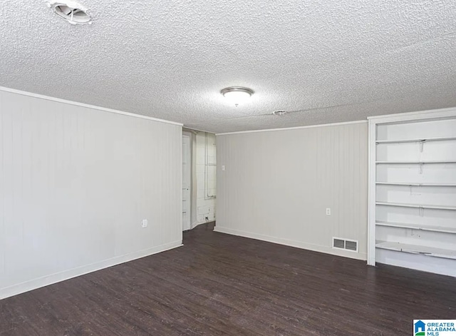 empty room featuring a textured ceiling, wooden walls, and dark hardwood / wood-style flooring