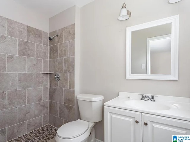 bathroom featuring tiled shower, toilet, and vanity