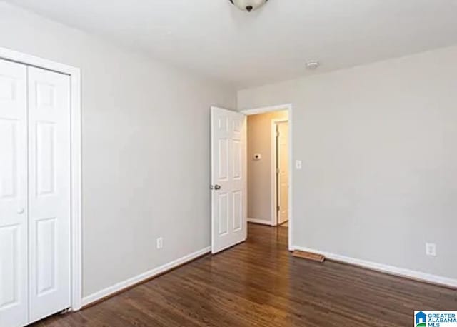 unfurnished bedroom featuring dark wood-type flooring and a closet