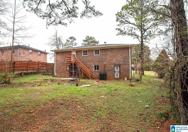 rear view of house featuring cooling unit and a yard