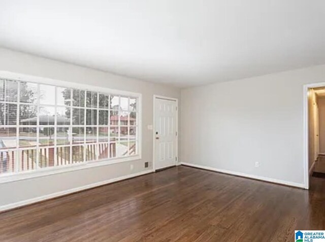 empty room with plenty of natural light and dark hardwood / wood-style floors