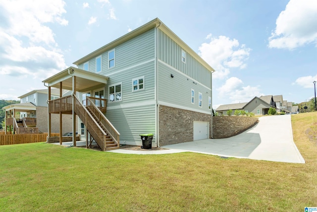 rear view of property featuring a garage, a lawn, and a wooden deck