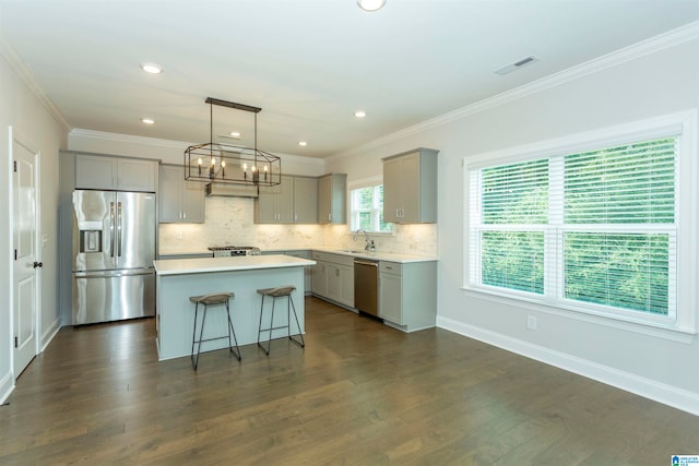 kitchen with a center island, appliances with stainless steel finishes, a notable chandelier, sink, and dark hardwood / wood-style floors