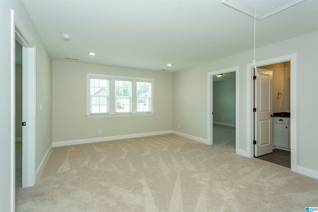 unfurnished bedroom with a walk in closet, connected bathroom, and light carpet