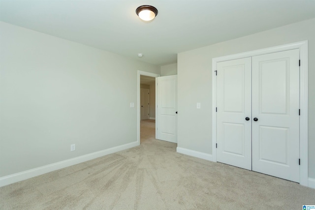 unfurnished bedroom featuring light colored carpet and a closet