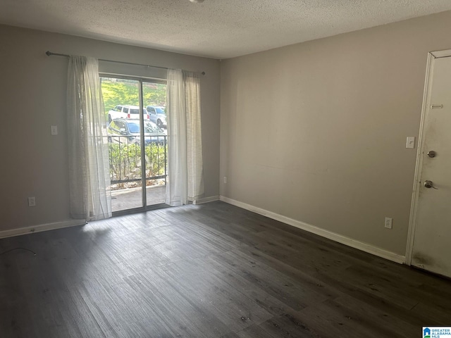 empty room with a textured ceiling and dark hardwood / wood-style floors