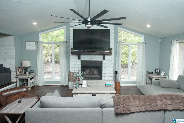 living room with a fireplace, dark hardwood / wood-style flooring, a textured ceiling, and vaulted ceiling