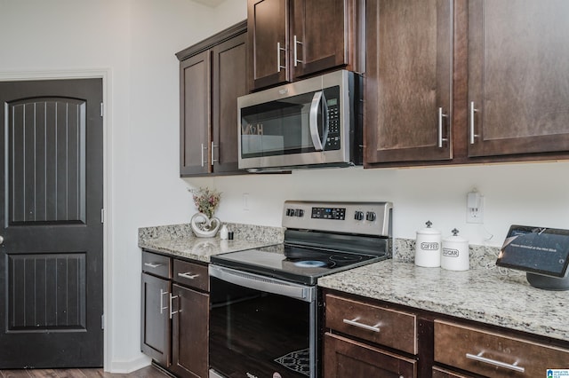 kitchen with light stone countertops, stainless steel appliances, and dark brown cabinets