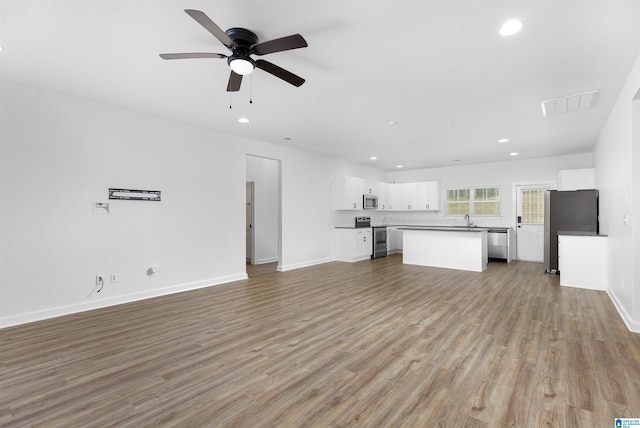 unfurnished living room featuring hardwood / wood-style floors, ceiling fan, and sink