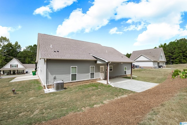 rear view of house with a lawn, a garage, a patio area, and central AC