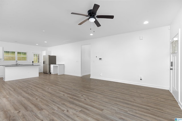 unfurnished living room featuring wood-type flooring, sink, and ceiling fan