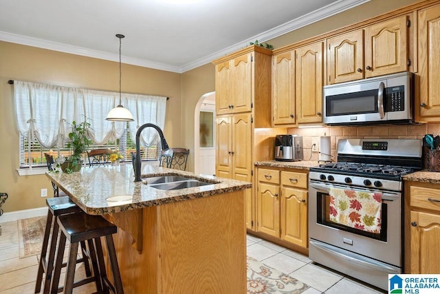 kitchen featuring a sink, stainless steel appliances, decorative backsplash, light stone counters, and arched walkways