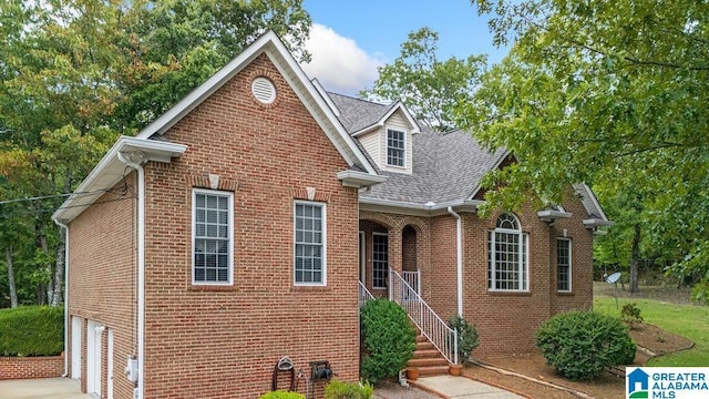 traditional home featuring concrete driveway, roof with shingles, an attached garage, and brick siding