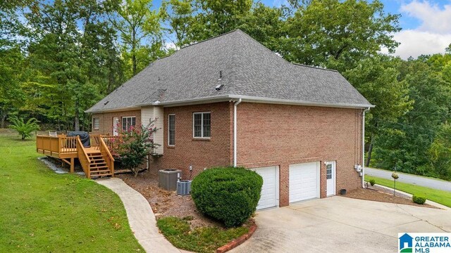 back of property with driveway, a wooden deck, an attached garage, a lawn, and brick siding