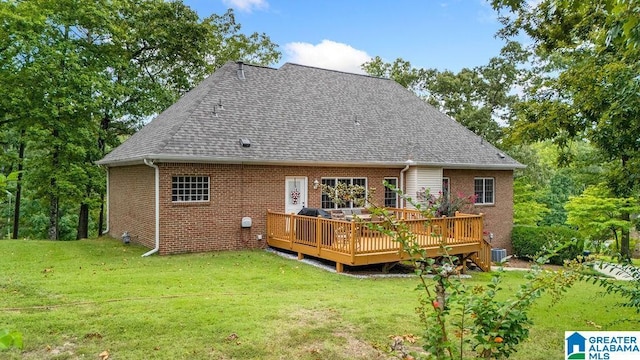 back of house featuring cooling unit, a lawn, brick siding, a deck, and roof with shingles