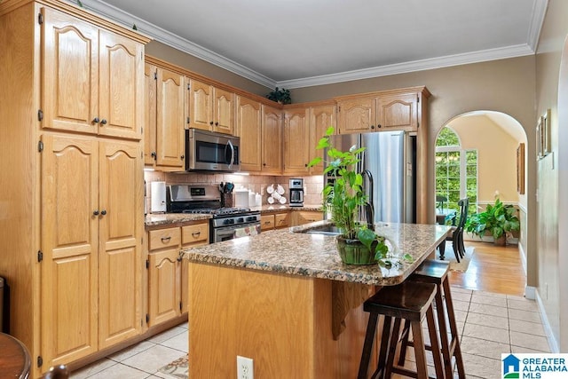 kitchen with light tile patterned floors, stainless steel appliances, decorative backsplash, and a sink