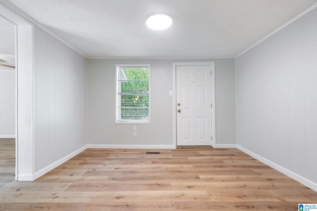 unfurnished room featuring crown molding, a textured ceiling, and light hardwood / wood-style floors