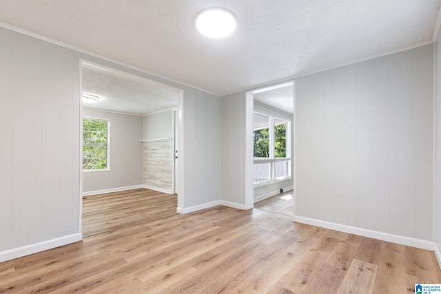 spare room with a textured ceiling, light hardwood / wood-style flooring, and ornamental molding