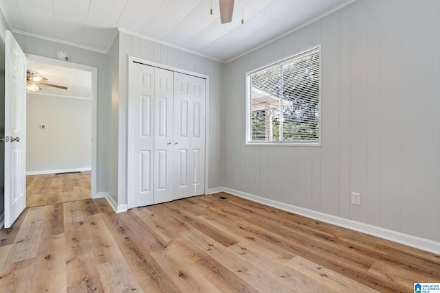 unfurnished bedroom with a closet, ceiling fan, crown molding, and light hardwood / wood-style flooring