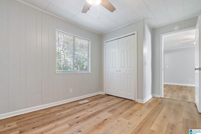 unfurnished bedroom featuring ceiling fan, ornamental molding, a closet, and light hardwood / wood-style floors