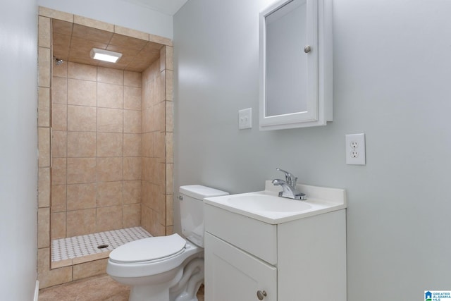 bathroom featuring vanity, toilet, tiled shower, and tile patterned floors