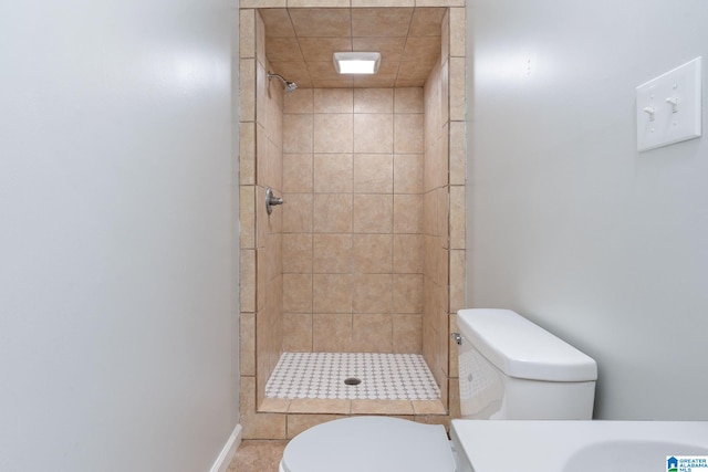 bathroom featuring toilet, a tile shower, and vanity