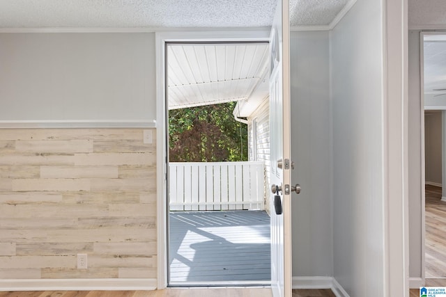 entryway featuring a textured ceiling, ornamental molding, hardwood / wood-style floors, and wooden walls