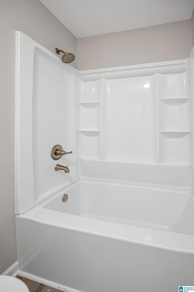 bathroom with hardwood / wood-style flooring and bathing tub / shower combination