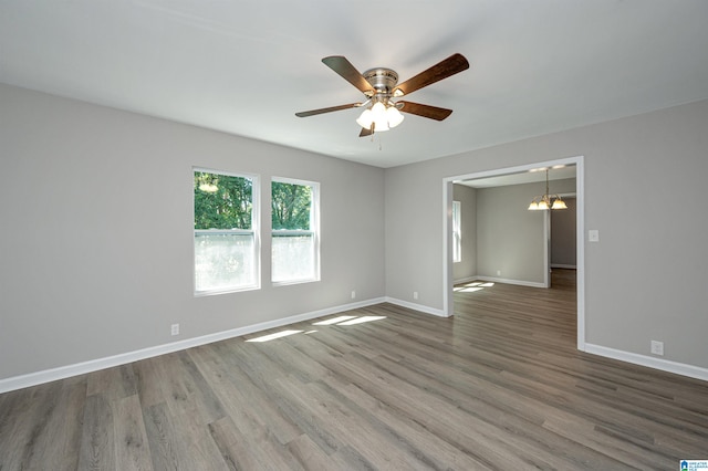 spare room featuring ceiling fan with notable chandelier and wood-type flooring