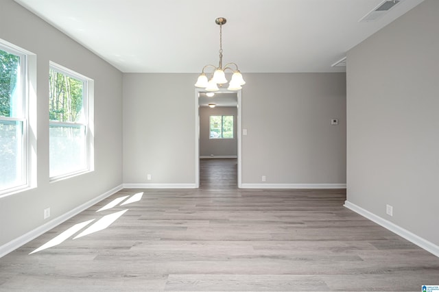 empty room with a chandelier and light hardwood / wood-style floors