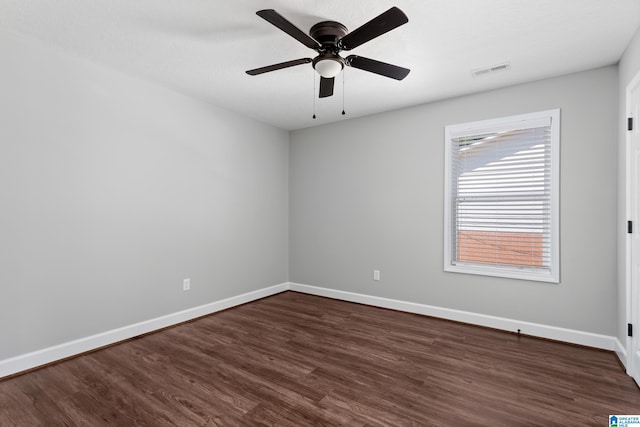 empty room featuring baseboards, ceiling fan, dark wood-type flooring, and visible vents