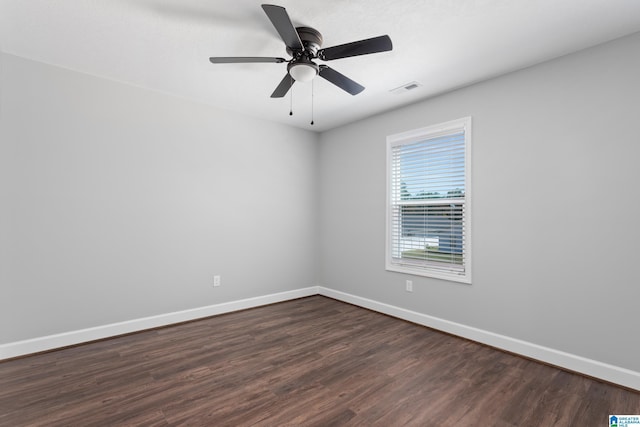 spare room with dark wood-style flooring, baseboards, visible vents, and a ceiling fan