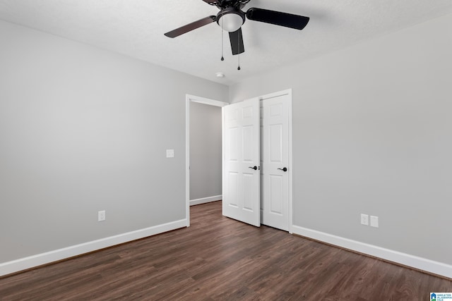 unfurnished bedroom with baseboards, a ceiling fan, and dark wood-style flooring