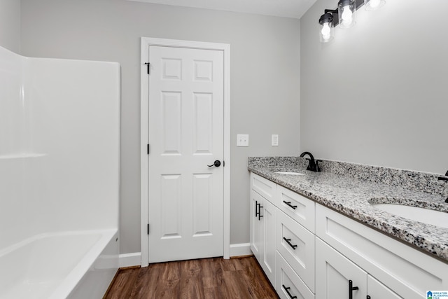 bathroom with a tub to relax in, hardwood / wood-style flooring, and vanity